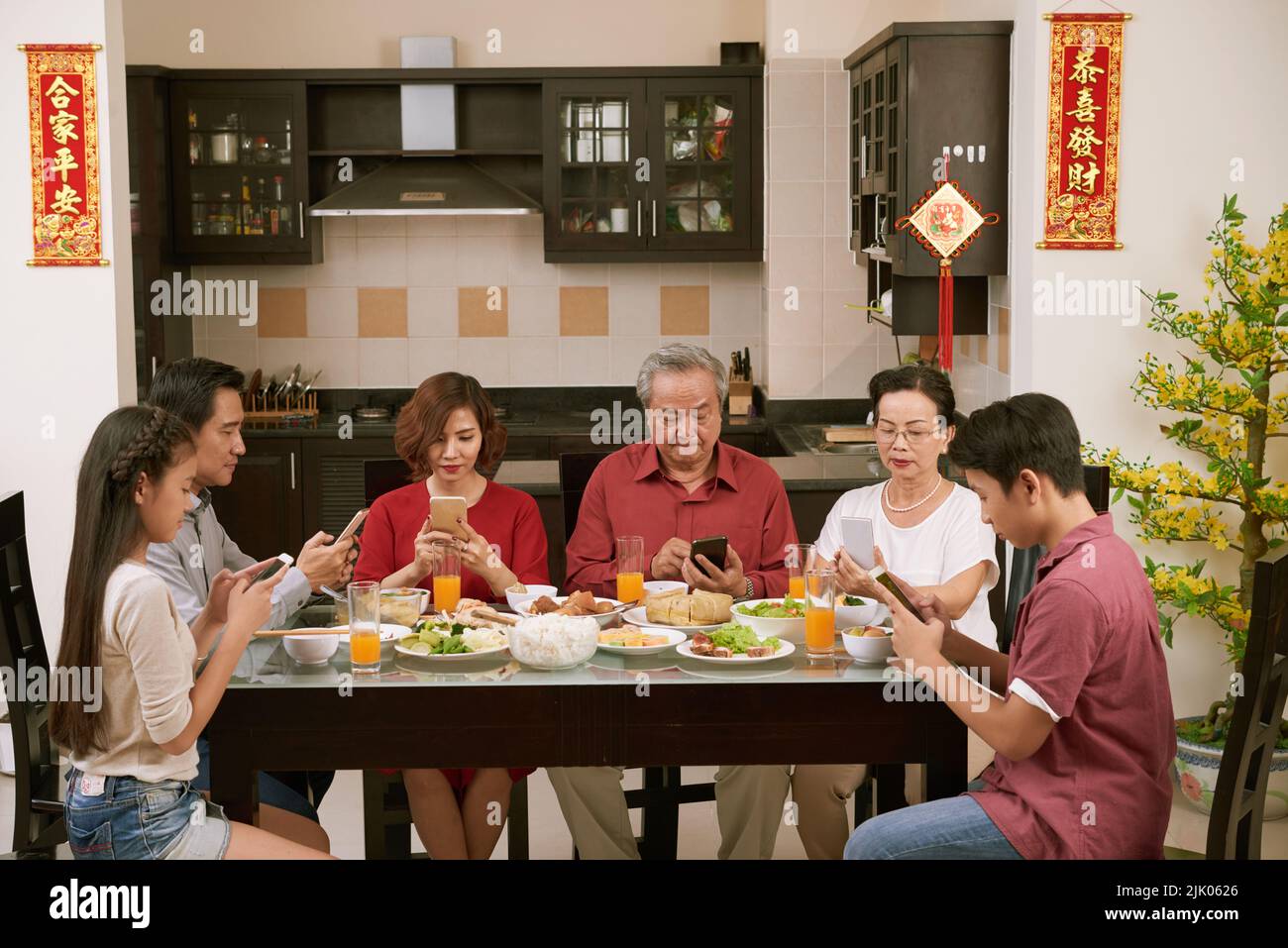 I membri della famiglia che controllano i loro smartphone alla celebrazione del Capodanno cinese. Scorre desiderio di fortuna e ricchezza in background Foto Stock