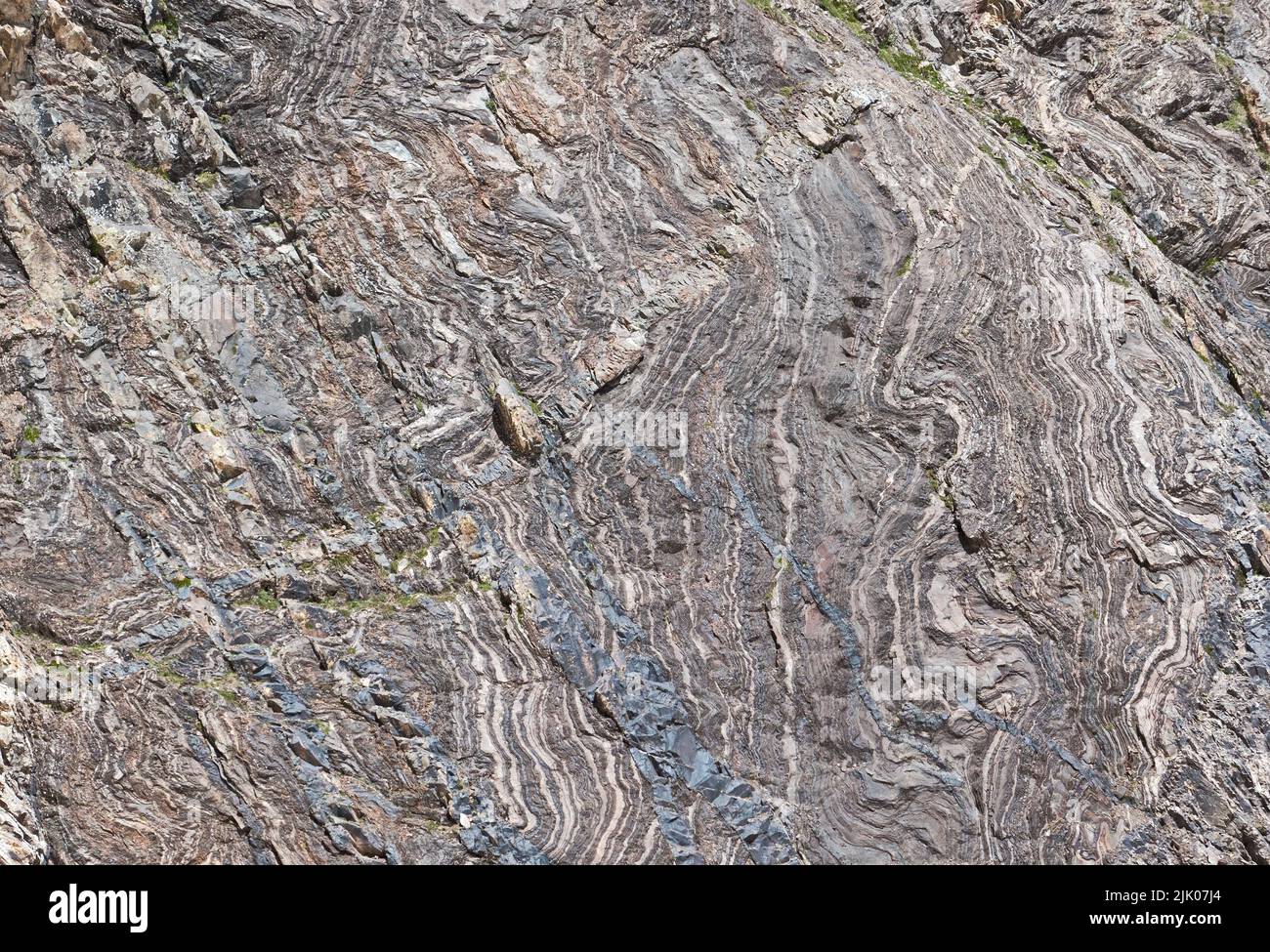 Dettaglio di strati grigi, deformati e curvi nella roccia, causati da forze geologiche, sfondo naturale Foto Stock