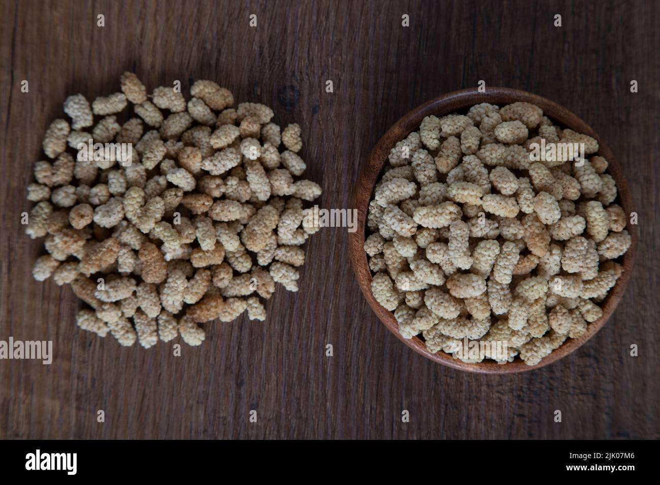 Ciotola piena di gelso secco su sfondo di legno Foto Stock