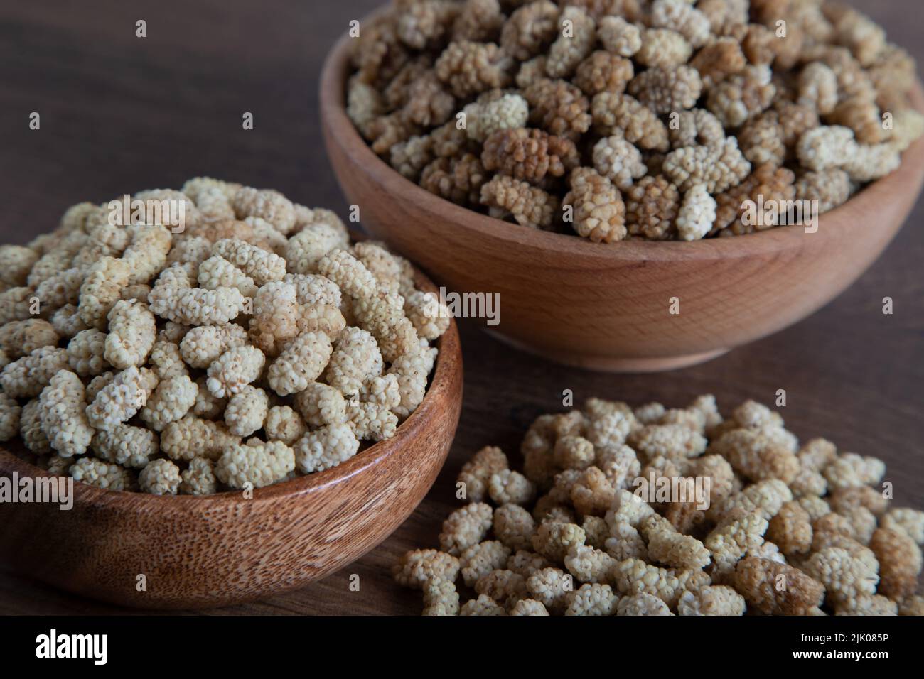 Ciotola piena di gelso secco su sfondo di legno Foto Stock