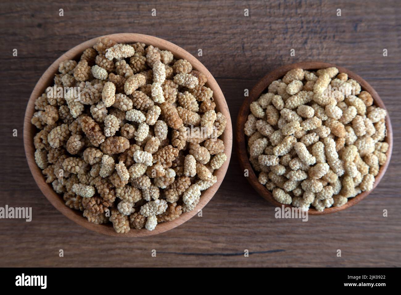 Ciotola piena di gelso secco su sfondo di legno Foto Stock