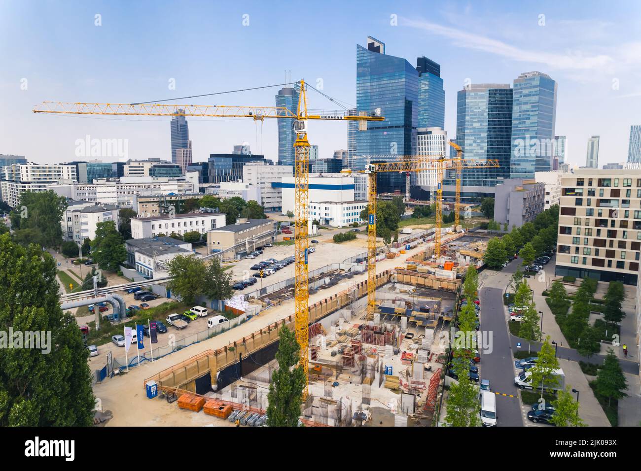 7.22.2022 Varsavia, Polonia. Quattro gru da cantiere gialle su un vasto cantiere che lavora a un nuovo progetto. Grattacieli sullo sfondo. Nuovo concetto di tenuta. Foto di alta qualità Foto Stock