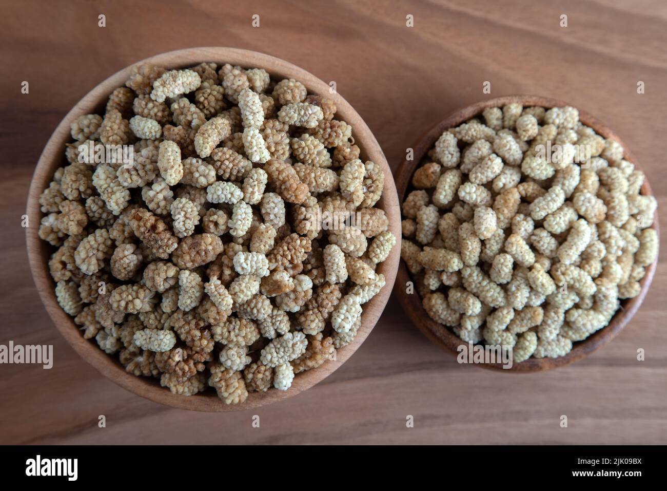 Ciotola piena di gelso secco su sfondo di legno Foto Stock