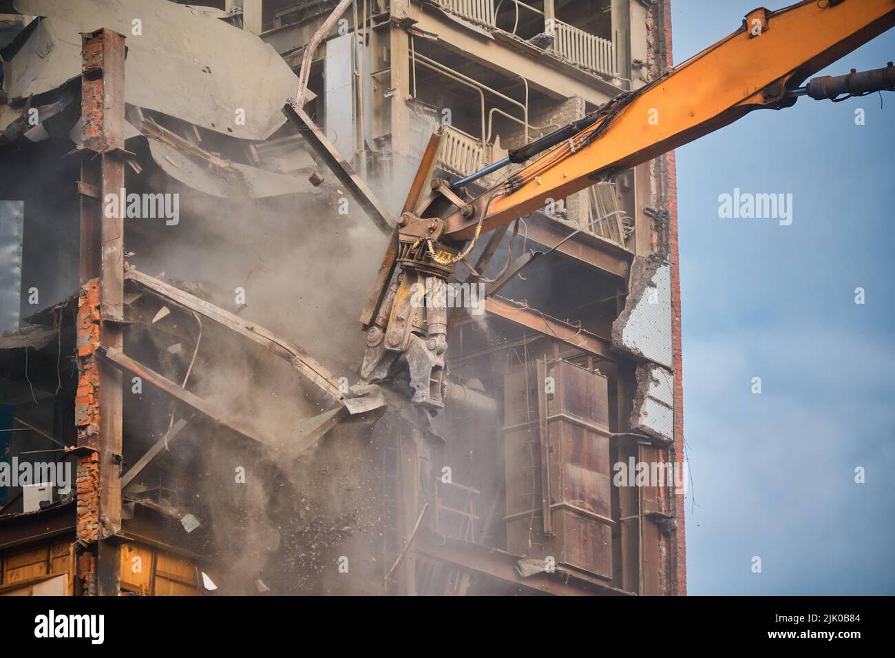 La fresa idraulica della gru demolisce il vecchio edificio industriale Foto Stock