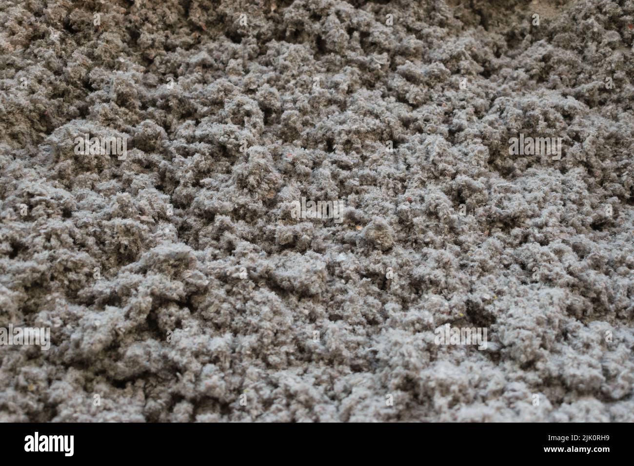 Iniezione ravvicinata di materiale isolante in cellulosa ecocompatibile tenuto in mano Foto Stock