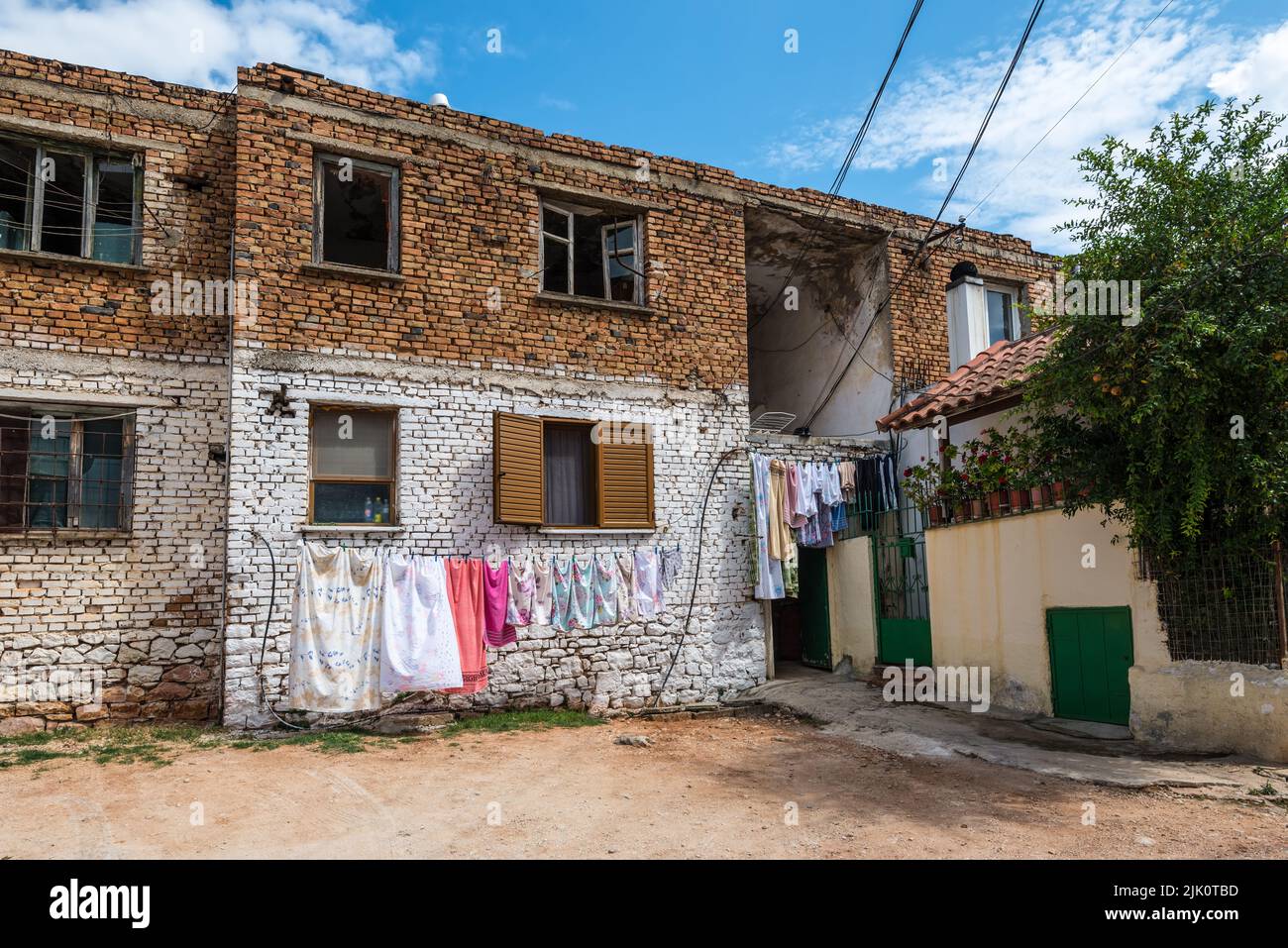 Ksamil, Albania - 9 settembre 2021: Vista sulla strada di Ksamil al giorno con la vecchia casa in una zona povera. La lavanderia è asciugata su una corda all'esterno. Foto Stock