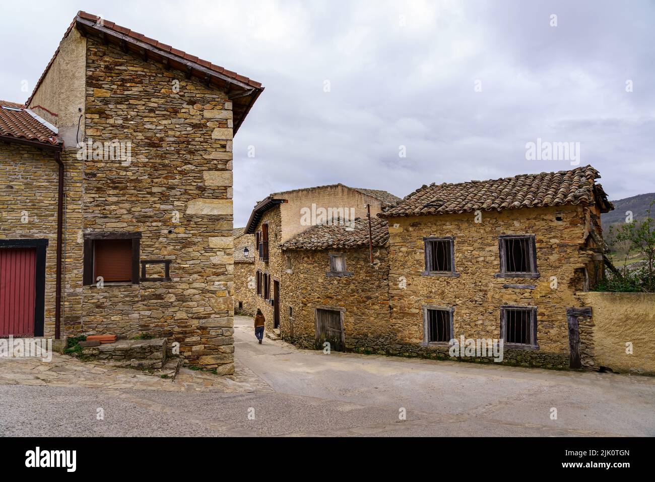 Persona che cammina in una strada stretta di una città vecchia medievale fatta di pietra. Horcajuelo Madrid. Spagna. Foto Stock
