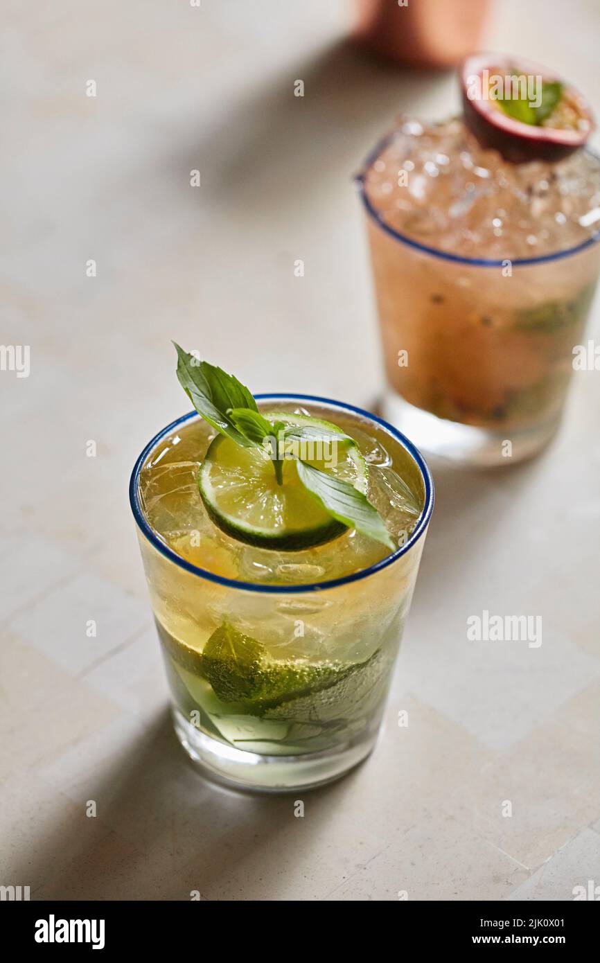 Due cocktail, uno con passionfruit e menta guarnito e uno con lime e menta Foto Stock