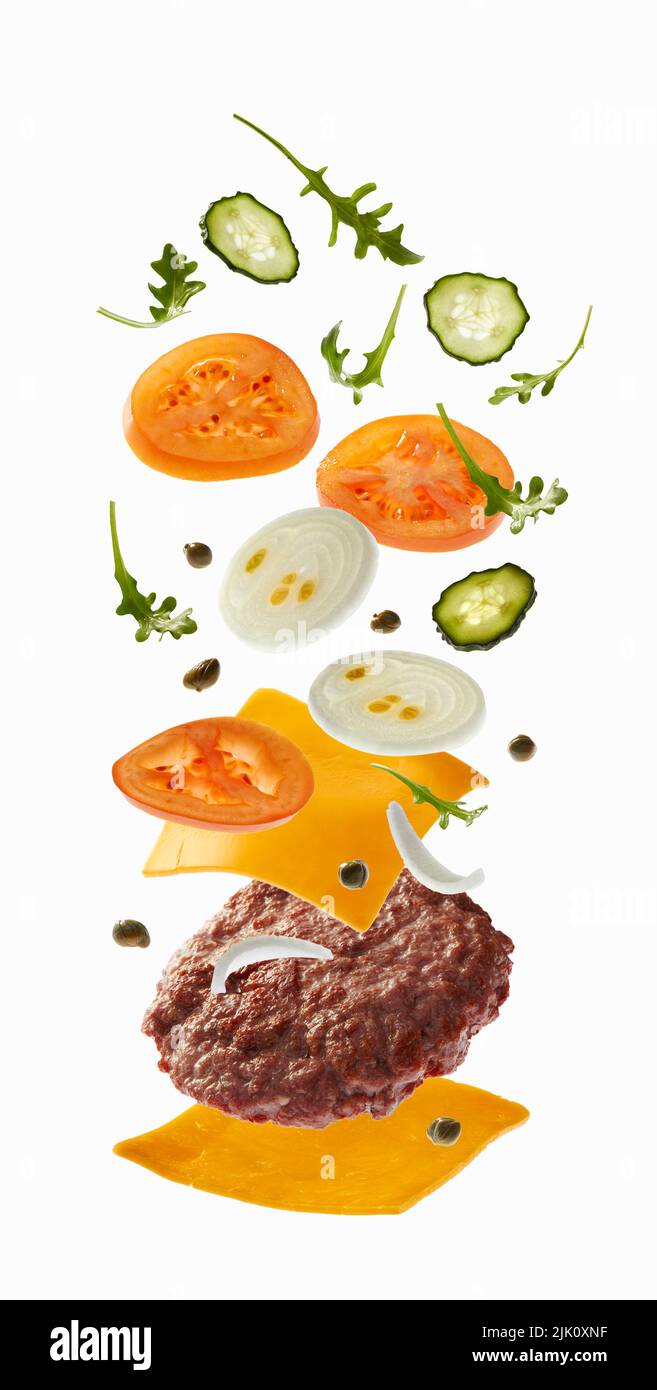 Hamburger con ingredienti volanti su sfondo bianco Foto Stock