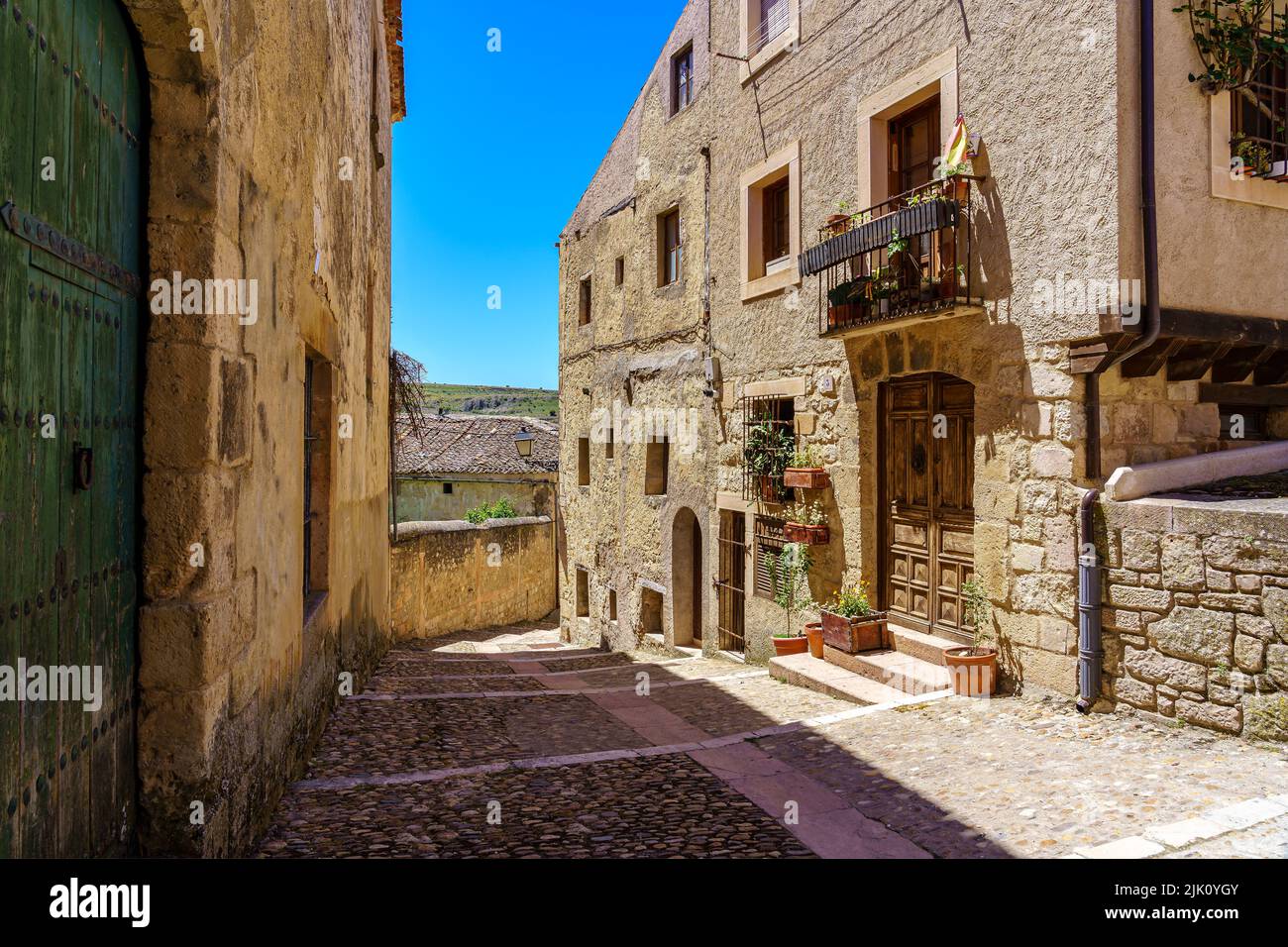 Strada stretta con le sue case in pietra in una giornata estiva soleggiata. Sepulveda Spagna. Foto Stock