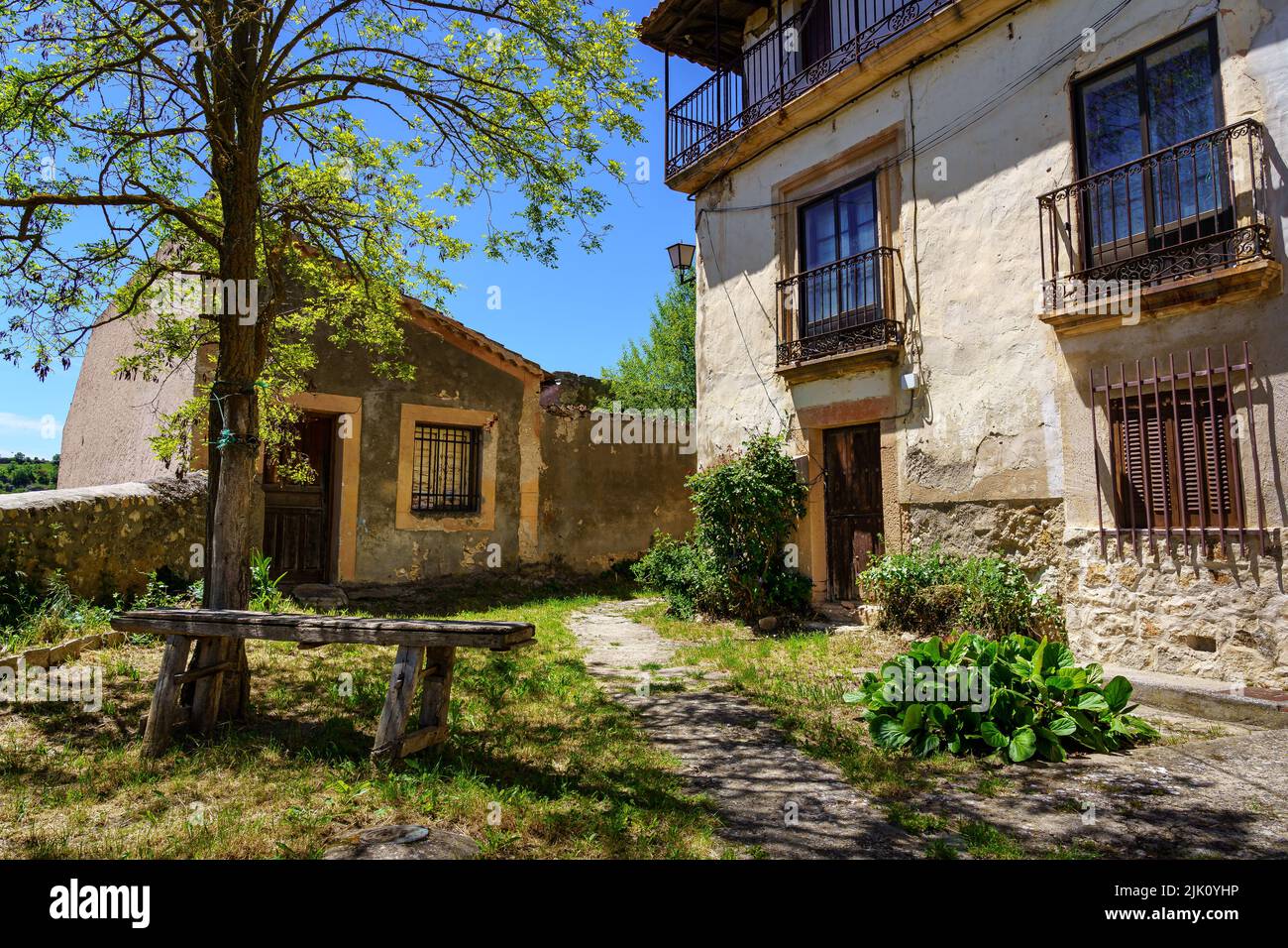 Facciata di vecchie case con piccolo giardino con vecchia panca in legno. Sepulveda Spagna. Foto Stock