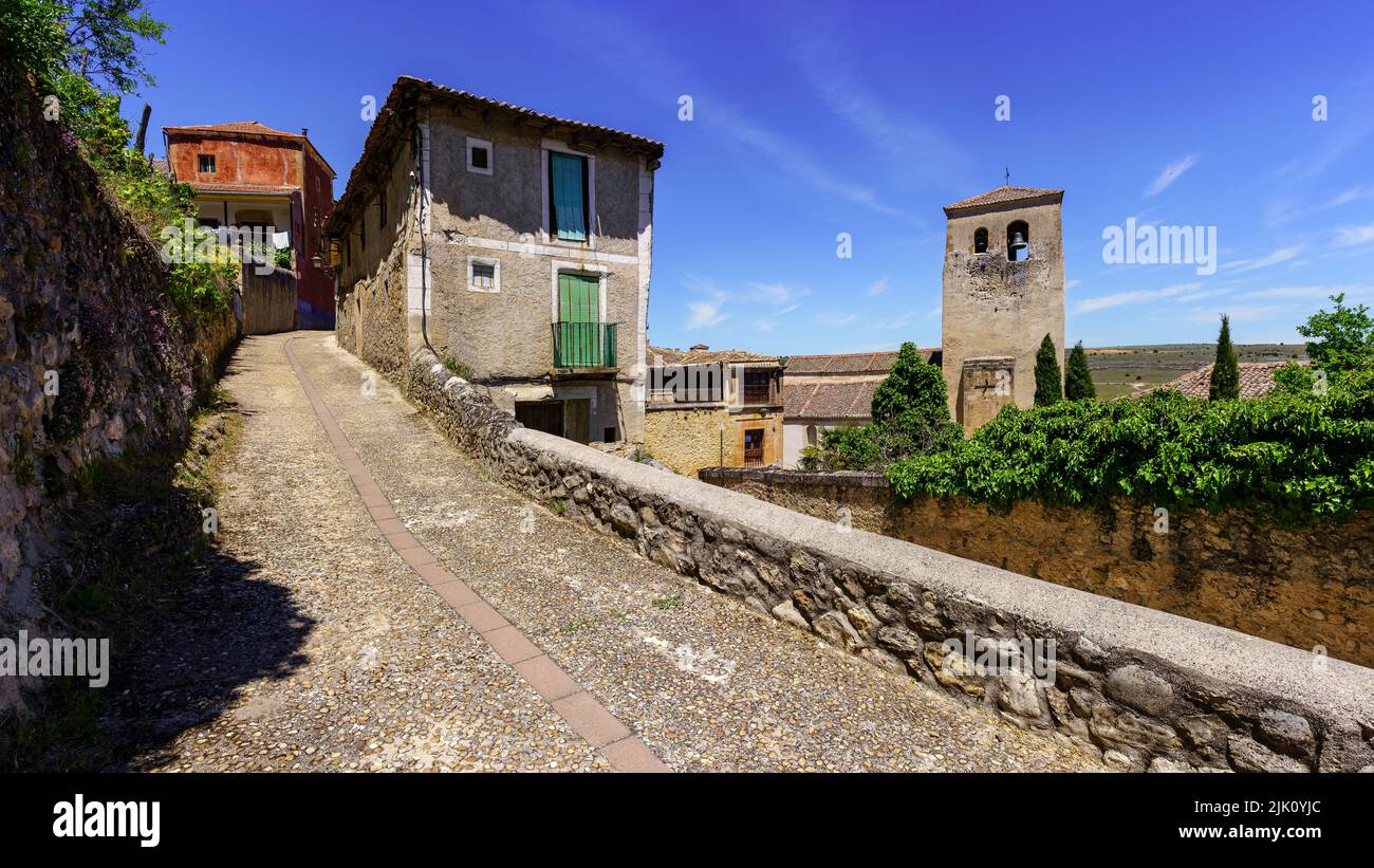 Panoramica di strada stretta della città vecchia con case in pietra e torre della chiesa. Foto Stock