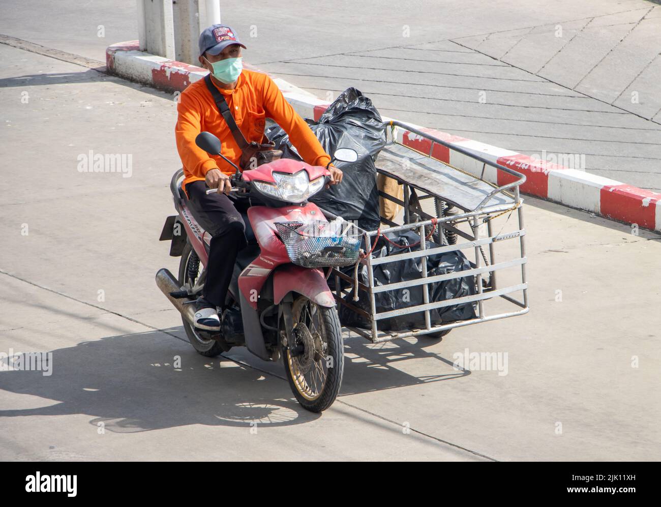 SAMUT PRAKAN, THAILANDIA, MAGGIO 30 2022, motociclista ride con carrello pieno di sacchetti di plastica con rifiuti riciclabili Foto Stock