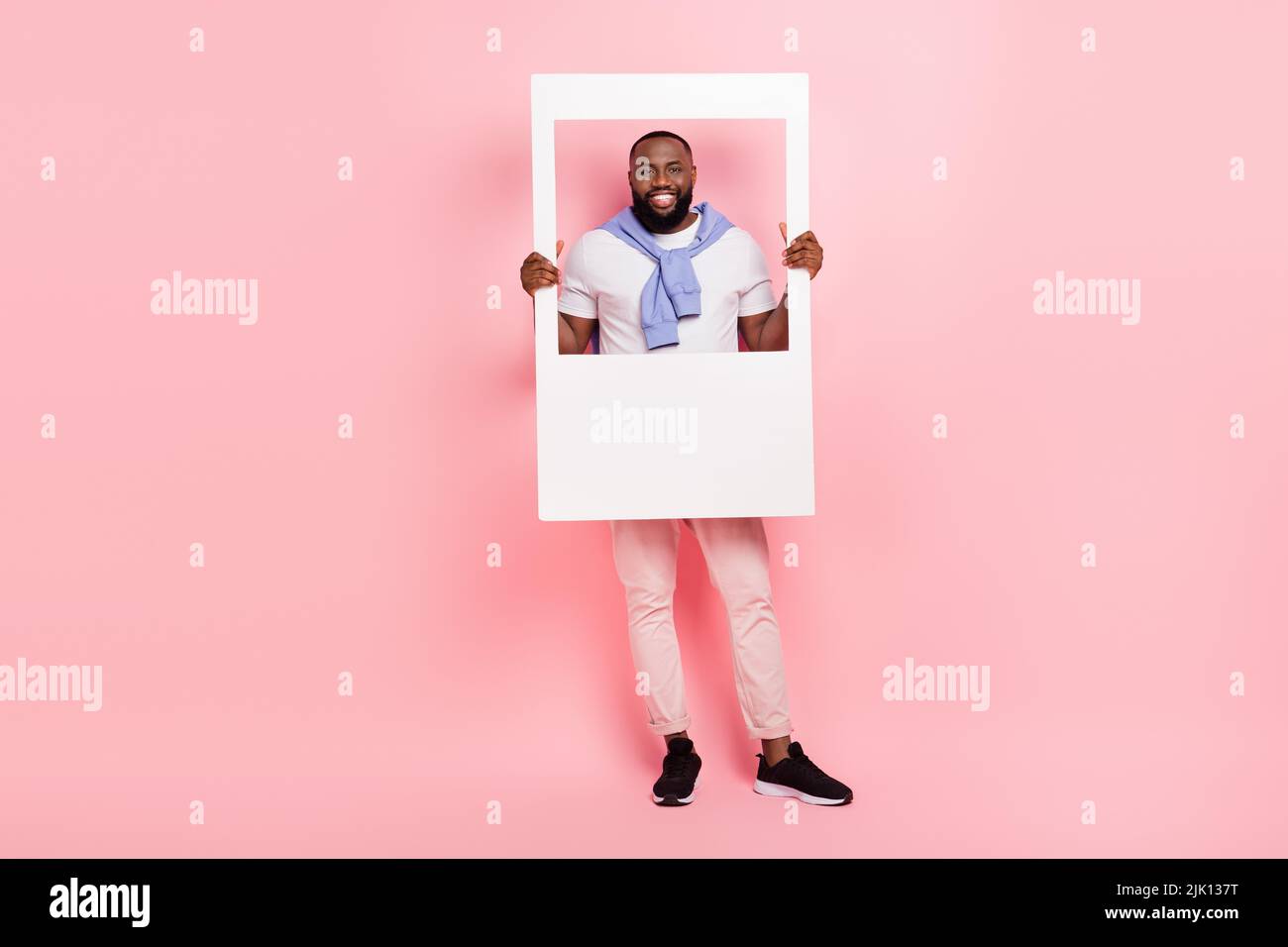 Foto a grandezza naturale del bel macho brutale uomo tenere foto polaroide di se stesso isolato su sfondo rosa Foto Stock