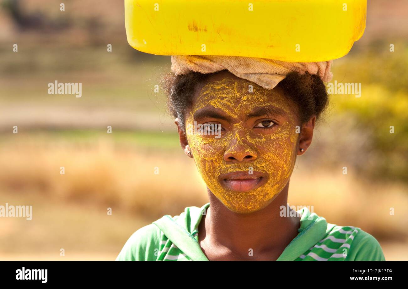Ritratto di donna che porta acqua, con il suo volto dipinto per proteggere la pelle dal sole, Isalo, Madagascar, Africa Foto Stock
