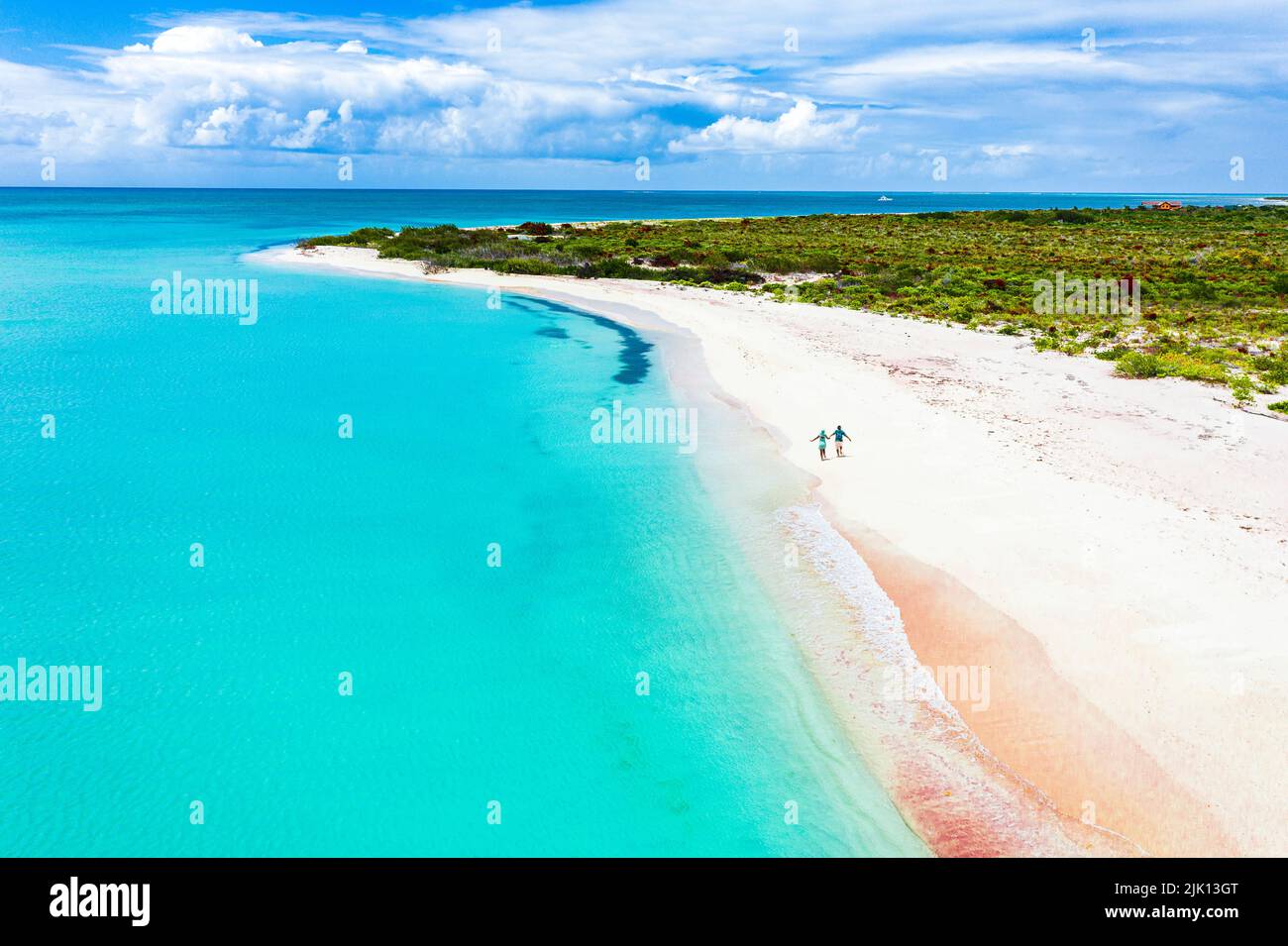 Uomo e donna che corre mano felice in mano su idilliaca spiaggia durante la luna di miele, vista dall'alto, Barbuda, Antigua e Barbuda, West Indies, Caraibi Foto Stock