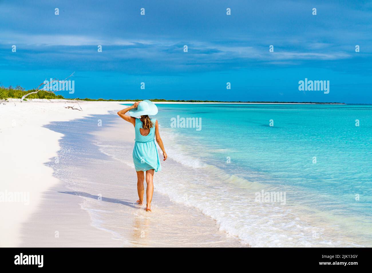 Bella donna che cammina su idilliaca spiaggia bagnata dal Mar dei Caraibi, Barbuda, Antigua e Barbuda, Indie Occidentali, Caraibi, America Centrale Foto Stock