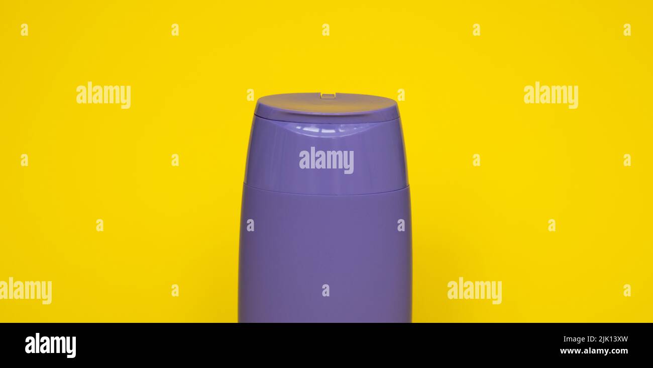 Bottiglia di plastica viola di prodotti per la cura del corpo e di bellezza. Studio fotografico di bottiglia di plastica per shampoo, gel doccia, crema isolato su giallo Foto Stock