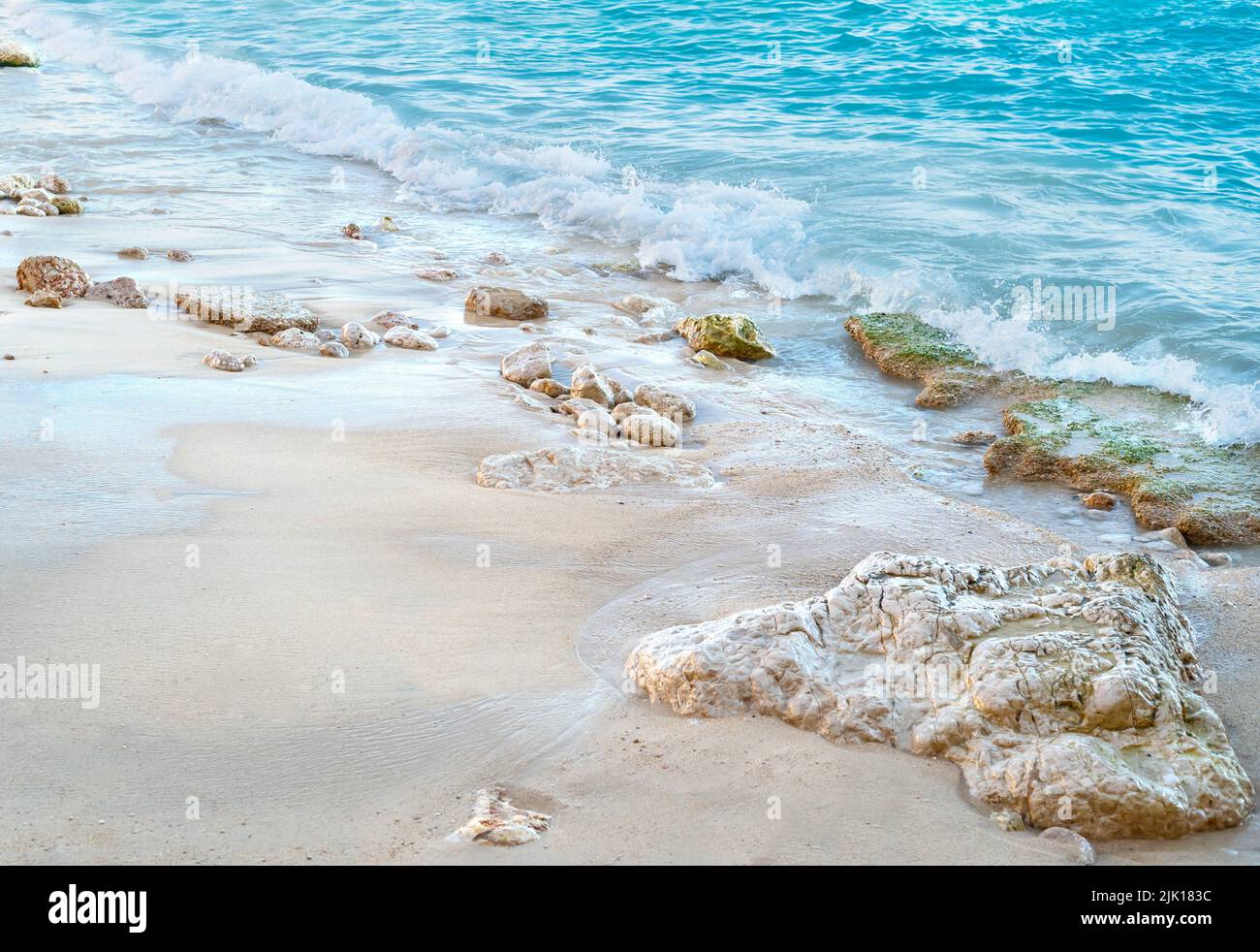 Primo piano foto spiaggia con calmanti colori di acqua, piccole rocce e sabbia pura come sfondo puro, di lusso vacanza estiva. Foto Stock