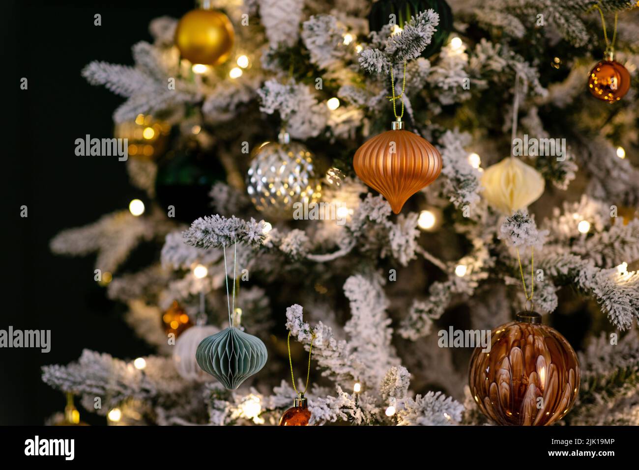 Primo piano di un albero di Natale decorato con palle e luci lucenti color oro-arancio. Foto Stock