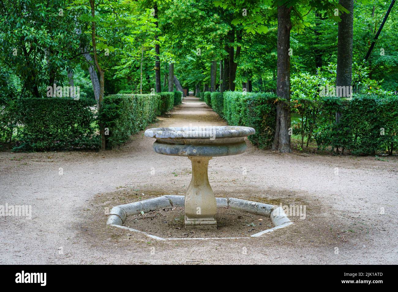 Angolo parco pubblico con una piccola fontana in pietra e vegetazione verde. Aranjuez Foto Stock