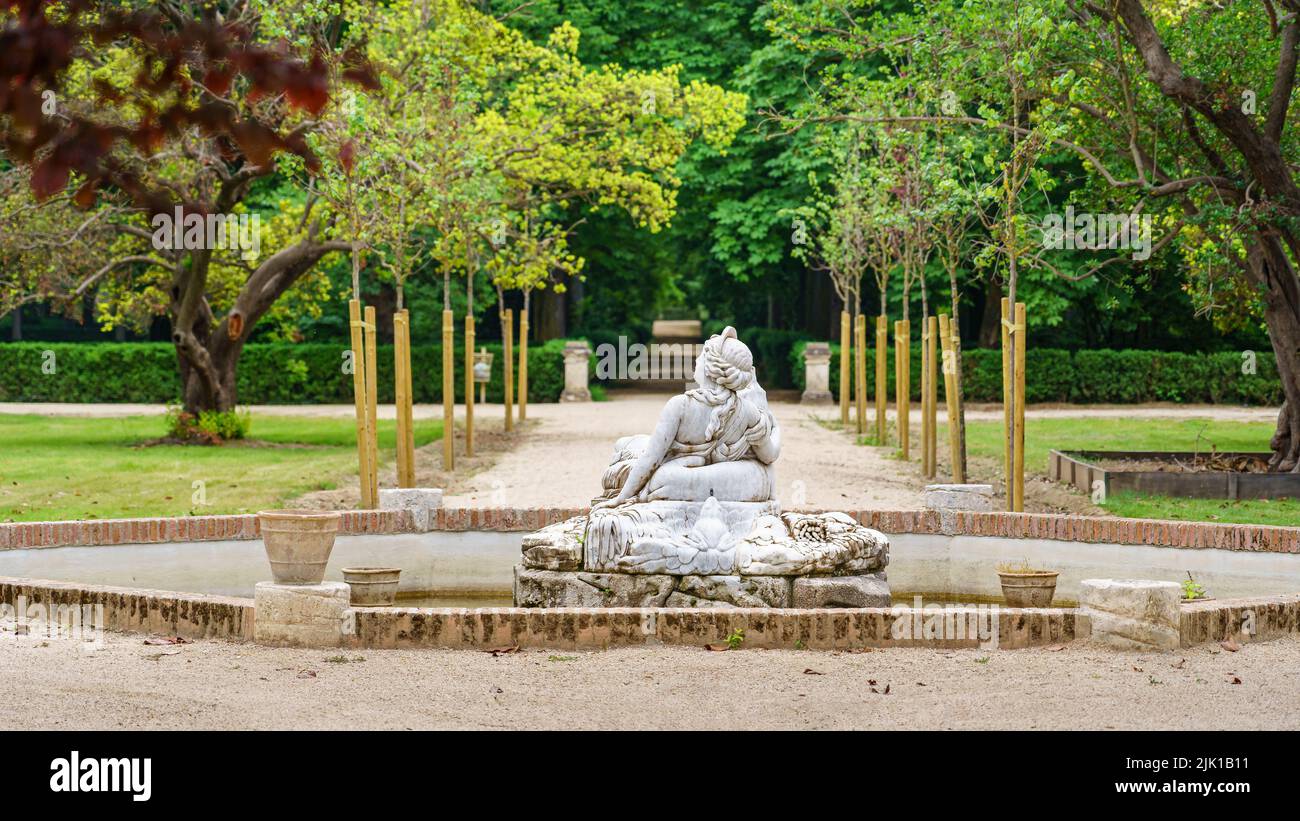 Fontana in pietra bianca con statua nel parco pubblico con vegetazione verde. Foto Stock