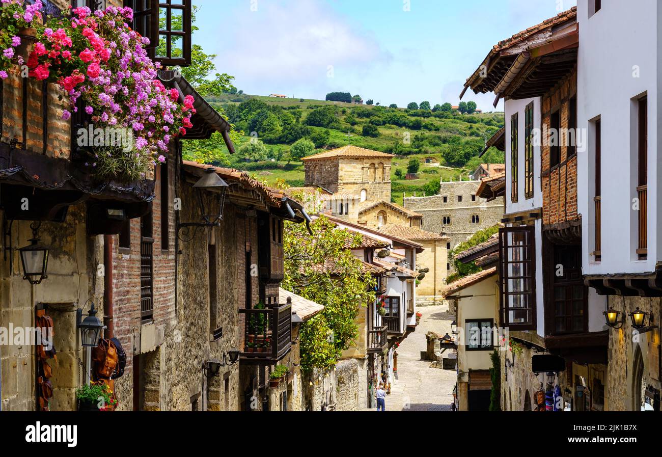 Vista prospettica delle case allineate in stretta strada della città vecchia e la chiesa sullo sfondo. Santillana del Mar, Santander. Foto Stock