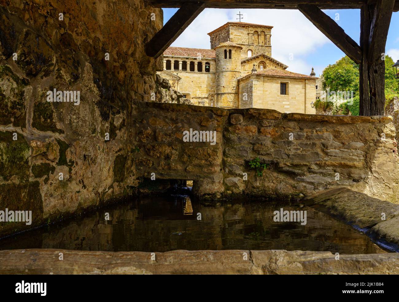 Fontana d'acqua dolce con chiesa in pietra nel centro storico medievale. Santillana del Mar, Santander. Foto Stock
