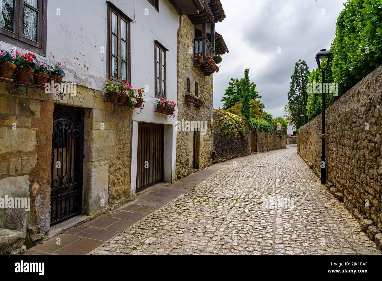 Vecchia strada villaggio in pietra con pareti coperte di verde e fiori. Santillana del Mar, Cantabria.. Foto Stock