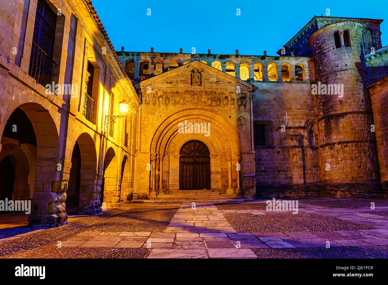 Porta di accesso principale alla chiesa medievale con torre e finestre ad arco. Santillana del Mar. Foto Stock