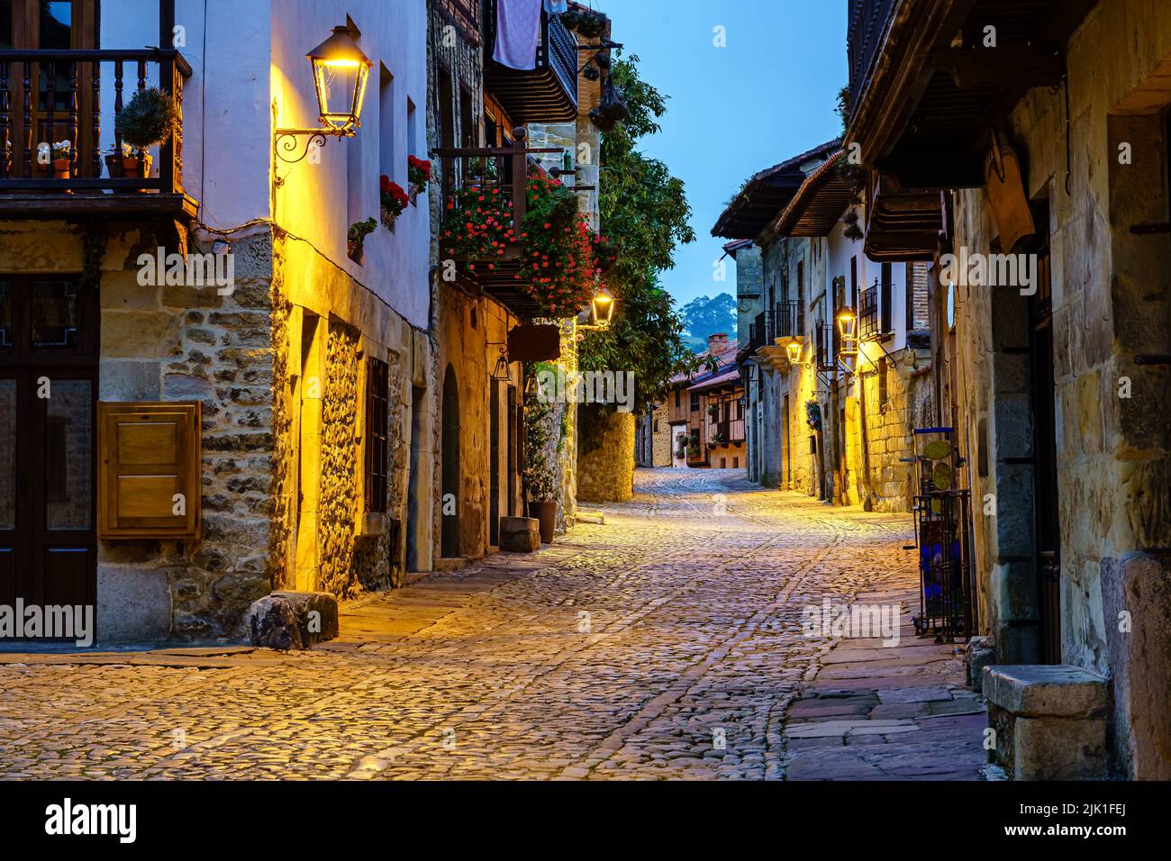 Vicolo stretto della città vecchia di pietra con strade acciottolate illuminate di notte. Foto Stock