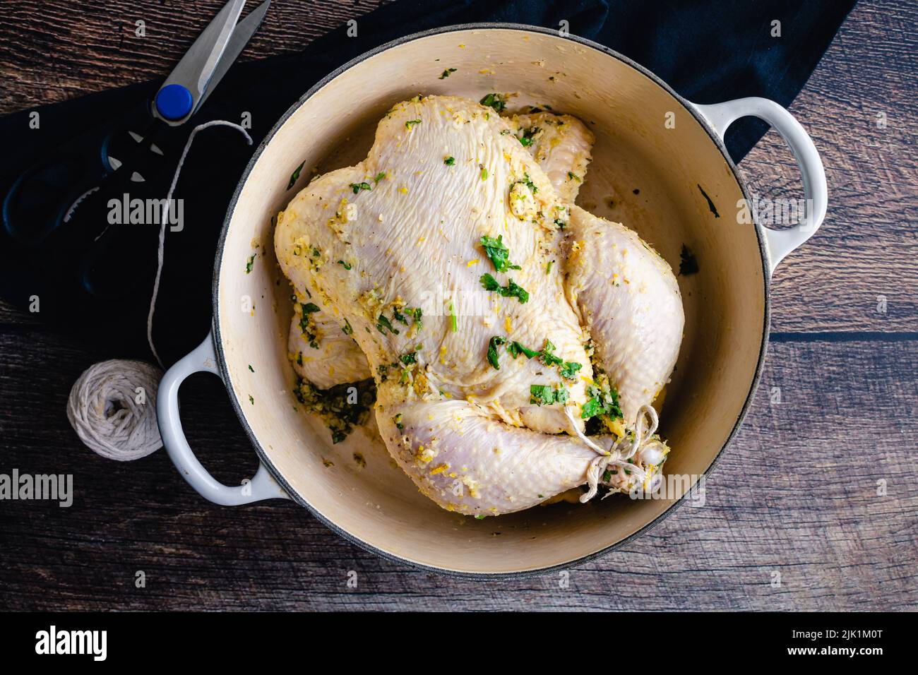 Pollo marinato di mojo cubano in un forno olandese: Un pollo crudo legato coperto in un forno olandese con erbe, aglio e marinata di agrumi Foto Stock