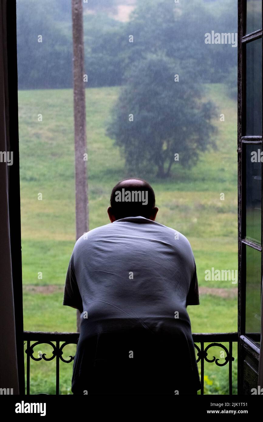 L'uomo guarda attraverso la finestra, pioggia Foto Stock