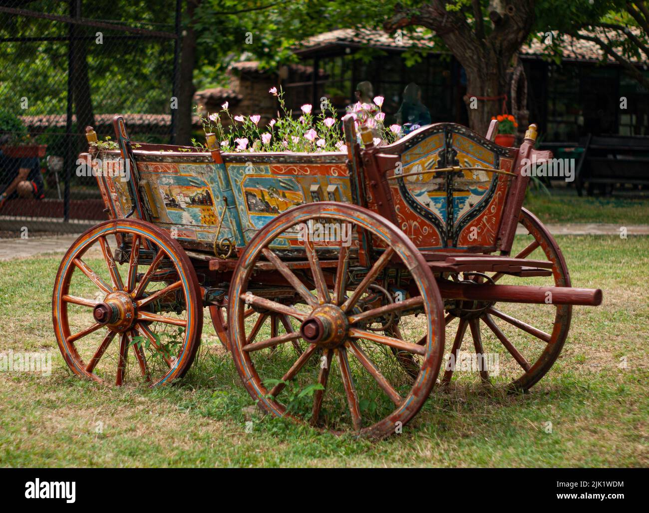Un vecchio carro o carro in legno in Bulgaria è dipinto con scene e simboli della campagna. I fiori stanno crescendo all'interno del carrello. Foto Stock