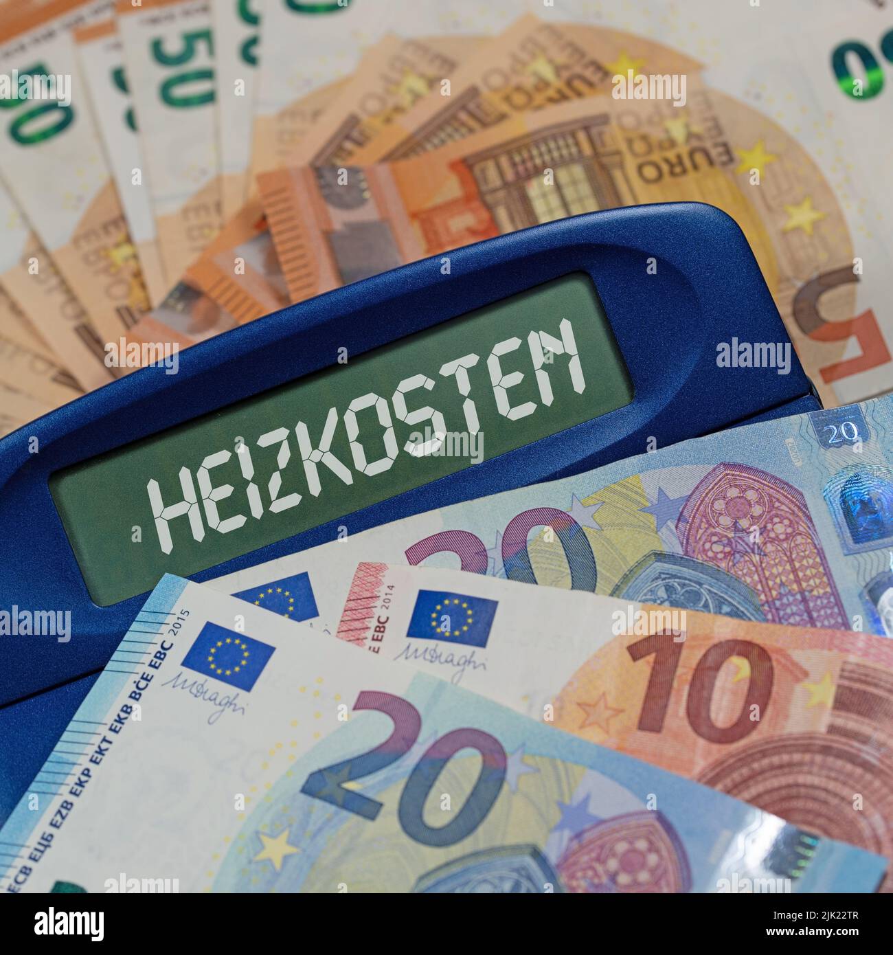 Calcolatrice con la parola 'Heizkosten', traduzione 'costi di riscaldamento' sul display di fronte alle banconote Foto Stock