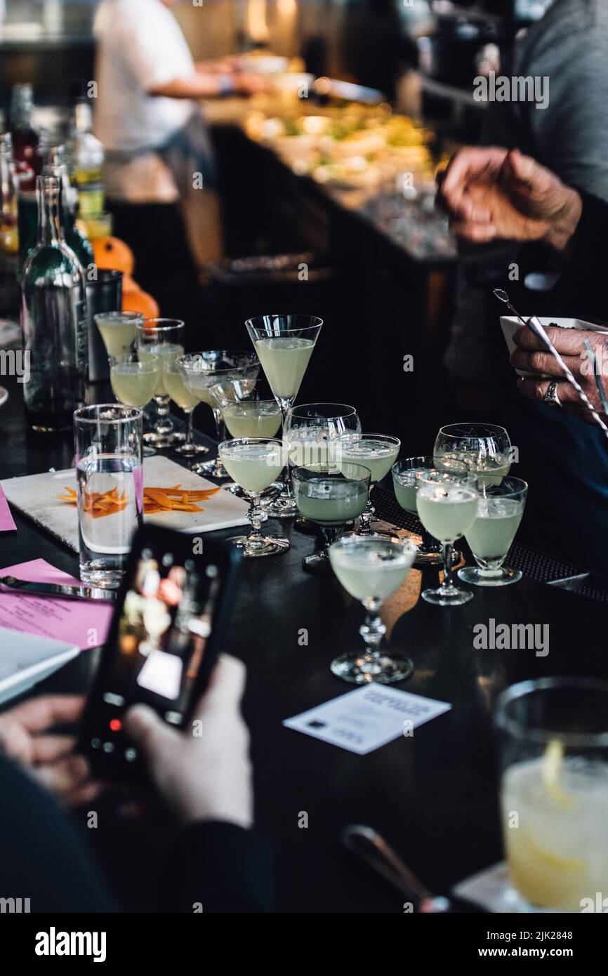 persona che scatta foto dello smartphone del barista che fa molti cocktail Foto Stock
