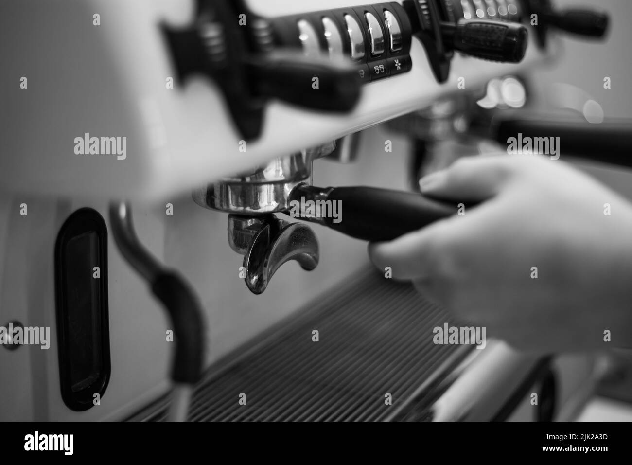 Il barista tiene in mano un portadocumenti e prepara il caffè con una macchina da caffè a doppia caldaia Foto Stock