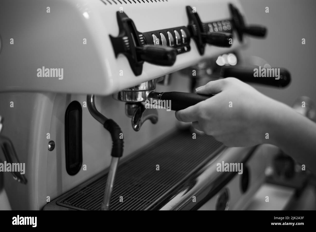 Il barista tiene in mano un portadocumenti e prepara il caffè con una macchina da caffè a doppia caldaia Foto Stock