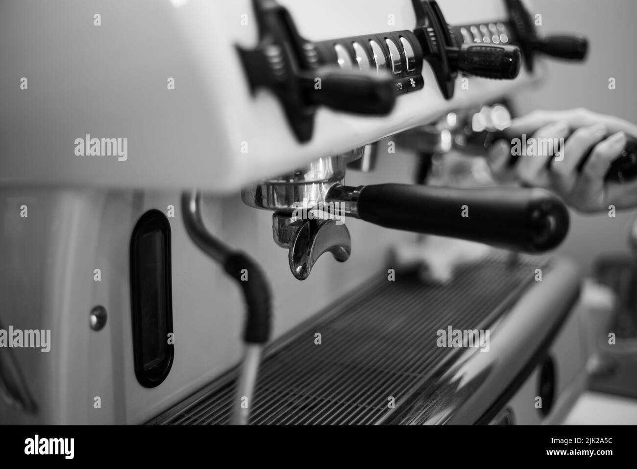 Il barista tiene in mano un portadocumenti e prepara il caffè con una macchina da caffè a doppia caldaia Foto Stock