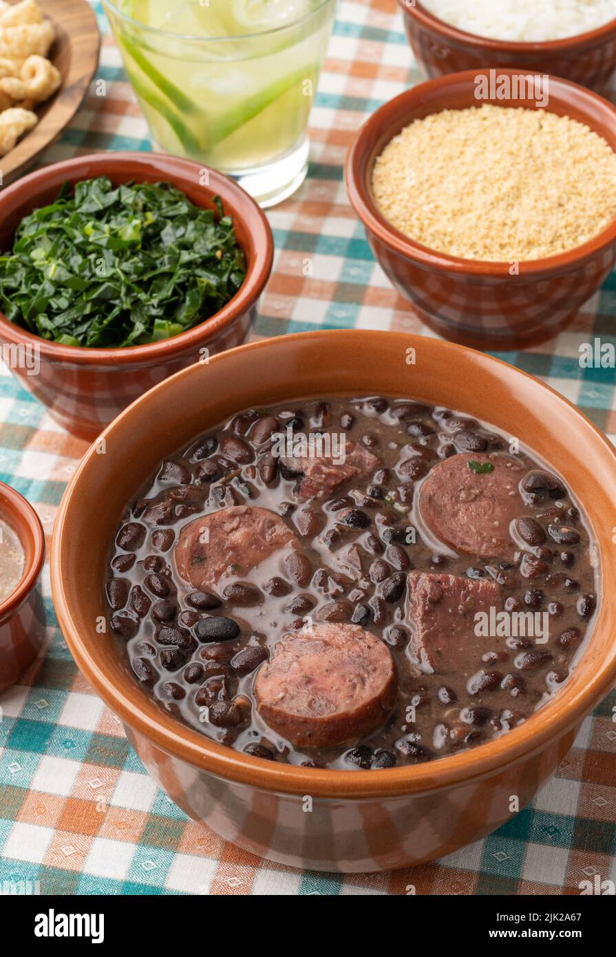 Tipica feijoada brasiliana con riso, caipirinha, farofa e cracklings. Foto Stock