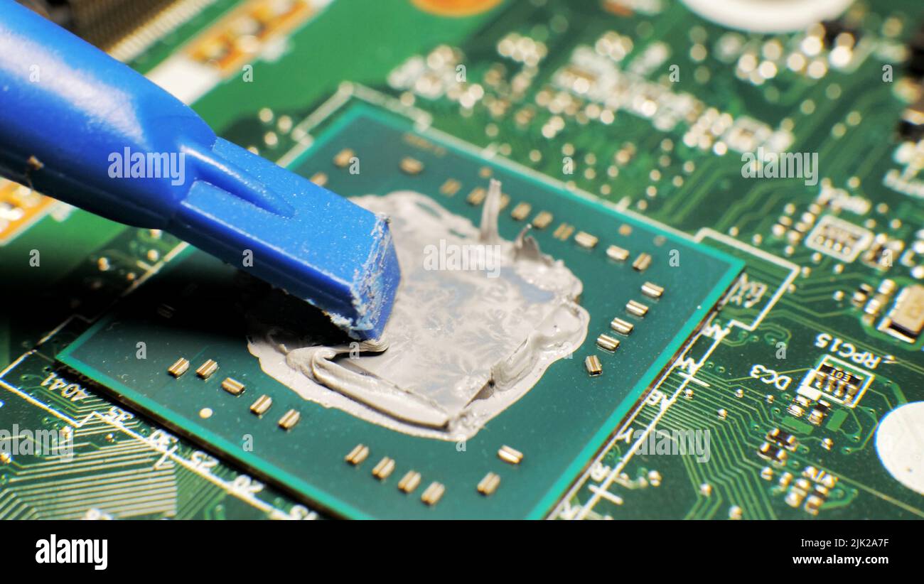 sostituzione, estrusione della pasta termica sul processore del laptop. Pasta termica per un migliore raffreddamento del dispositivo Foto Stock