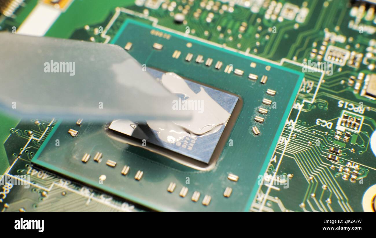 sostituzione, estrusione della pasta termica sul processore del laptop. Pasta termica per un migliore raffreddamento del dispositivo Foto Stock