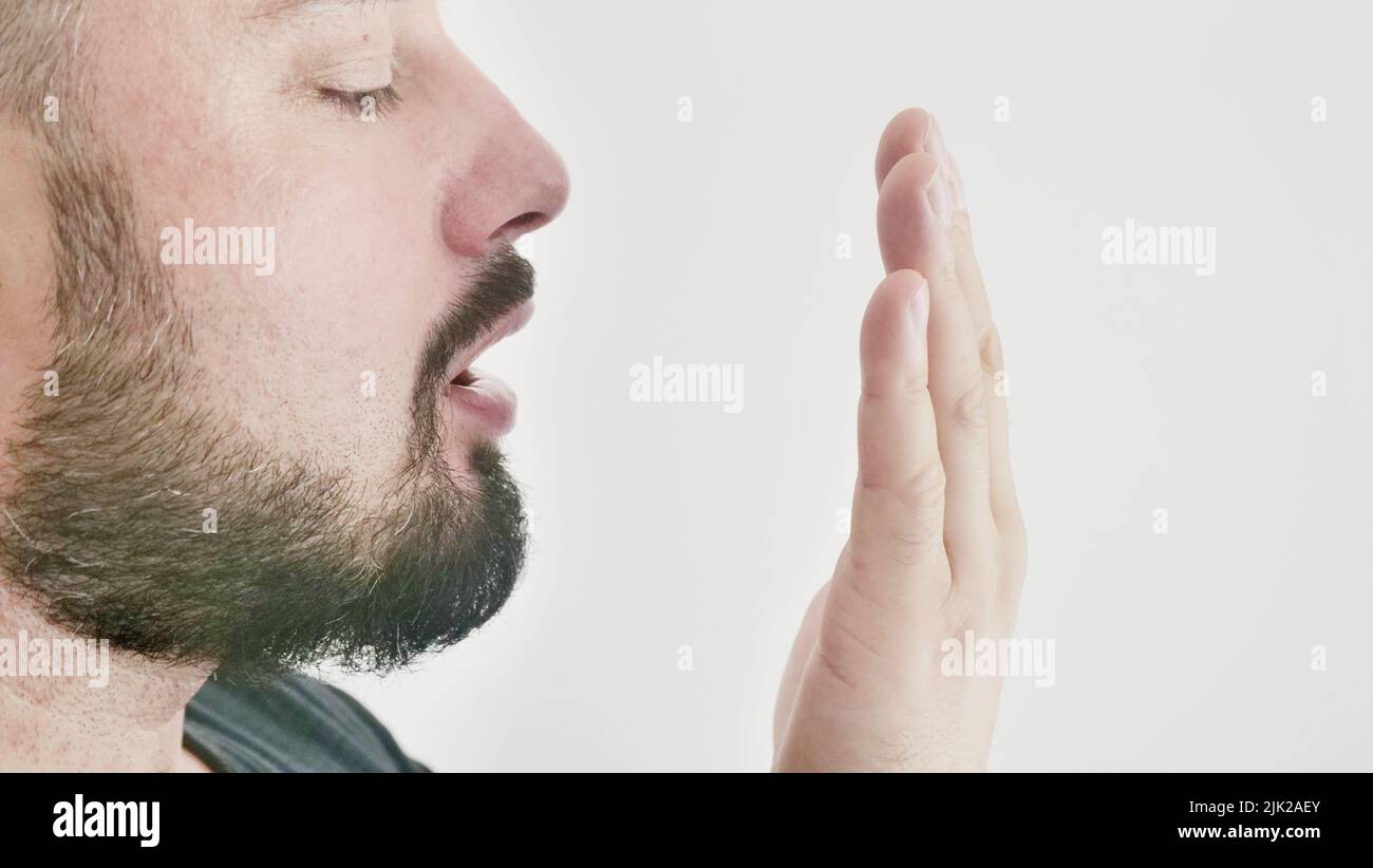 Alito cattivo. Il concetto di alitosi. Un giovane controlla il respiro con la mano Foto Stock