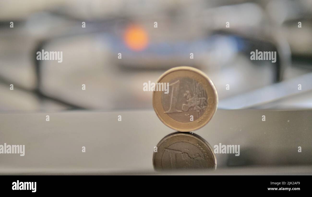Una moneta in euro sullo sfondo di una fiamma a gas che simboleggia il pagamento delle merci Foto Stock