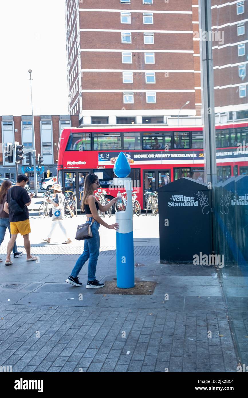 Londra, 2022 luglio: Una donna che riempie una bottiglia d'acqua riutilizzabile presso una fontana di Shepherds Bush Foto Stock
