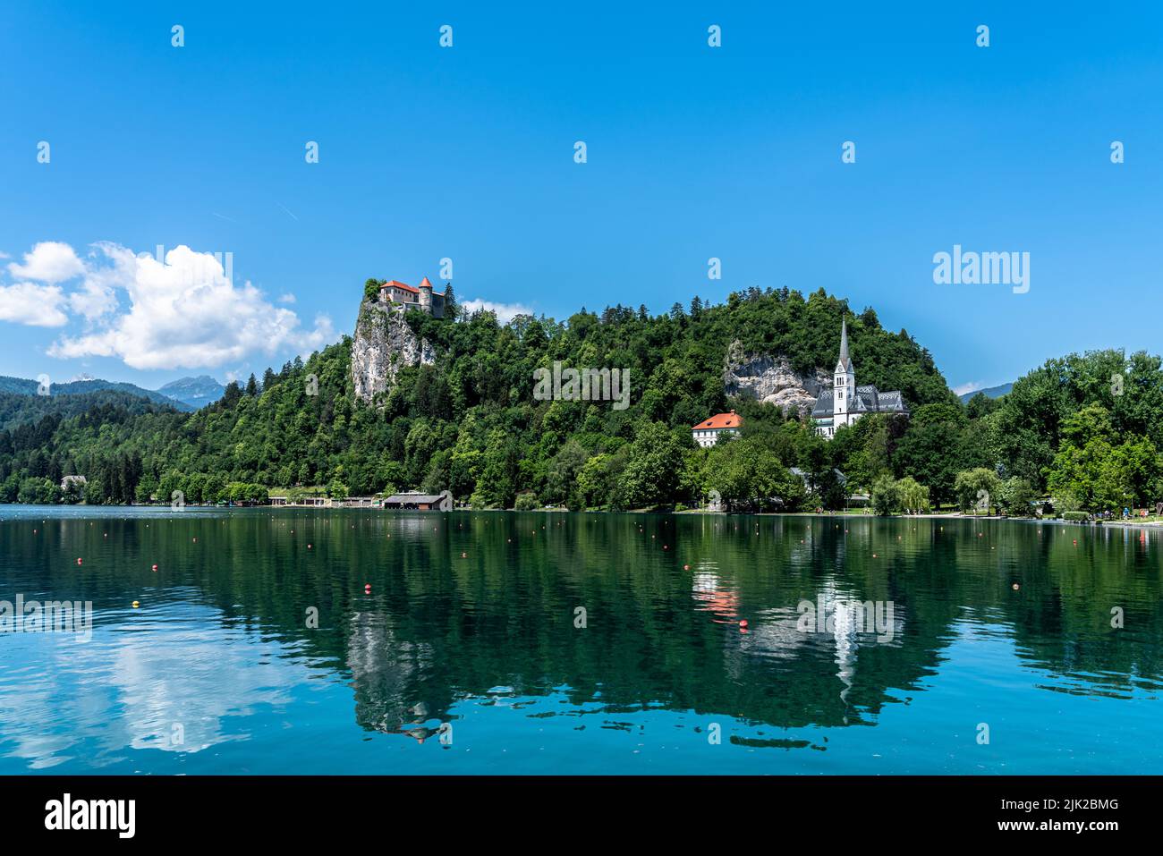 Splendida vista panoramica idilliaca del lago di Bled con il castello di Bled, la chiesa parrocchiale di San Martino e le Alpi slovene sullo sfondo durante la giornata estiva con il bl Foto Stock