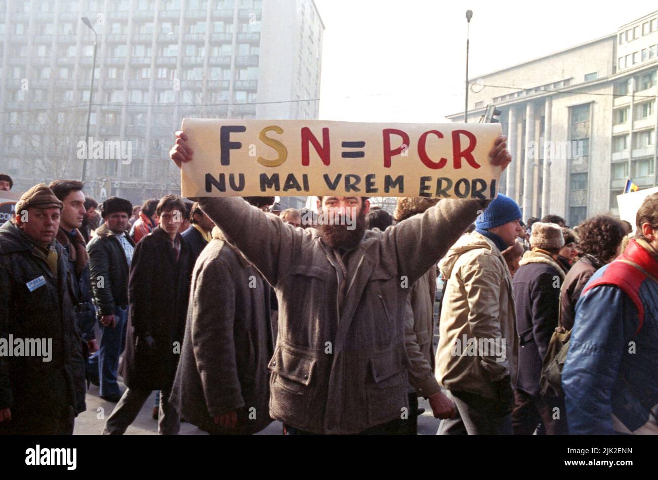 Bucarest, Romania, 28 gennaio 1990. Un mese dopo la rivoluzione anticomunista, i sostenitori dei partiti storici (di destra) marciano contro il nuovo partito politico al potere, F.S.N., composto principalmente da ex ufficiali comunisti. Un uomo ha un banner che dice ' F.S.N.= P.C.R. (Partito comunista rumeno). Niente più errori". Foto Stock