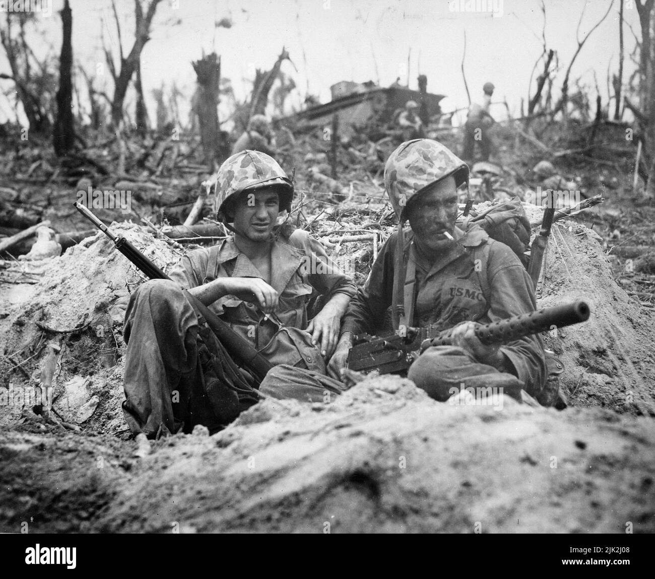 Marine Private First Class Douglas Lightheart (a destra) porta in braccio una mitragliatrice di calibro 30, mentre lui e il suo amico privato First Class Gerald Churchby prendono tempo per una sigaretta, mentre tagliano il nemico sulle Isole Peleliu Foto Stock