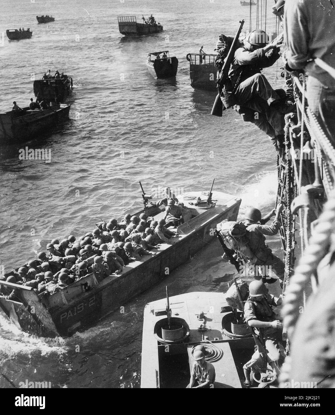 Le truppe degli Stati Uniti vanno oltre il lato di un trasporto di combattimento presidiato della Guardia Costiera per entrare nelle chiatte di atterraggio a Empress Augusta Bay, Bougainville, come l'invasione è in corso nel novembre 1943. Foto Stock