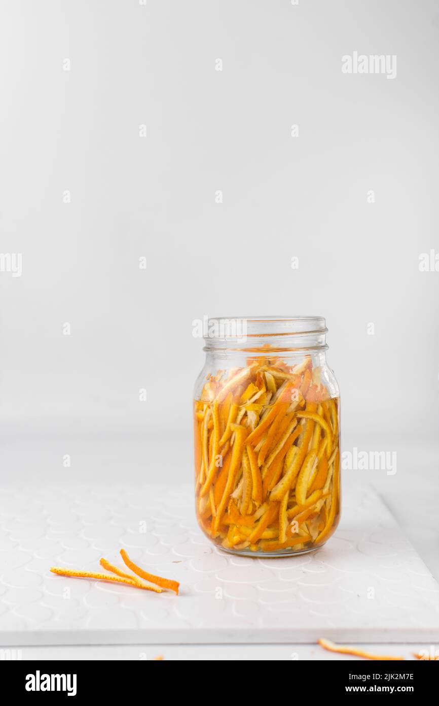 Preparazione dell'estratto d'arancia, buccia d'arancia in un vasetto di vetro, scorza d'arancia tagliata a fette Foto Stock